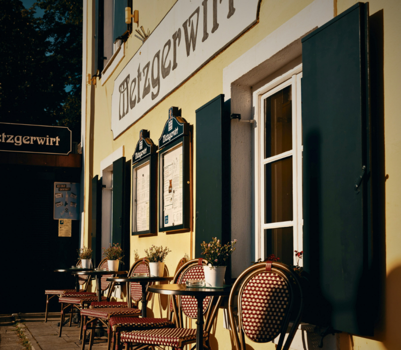 Chair and tables lined up outside a German café with yellow painted walls and green window shutters